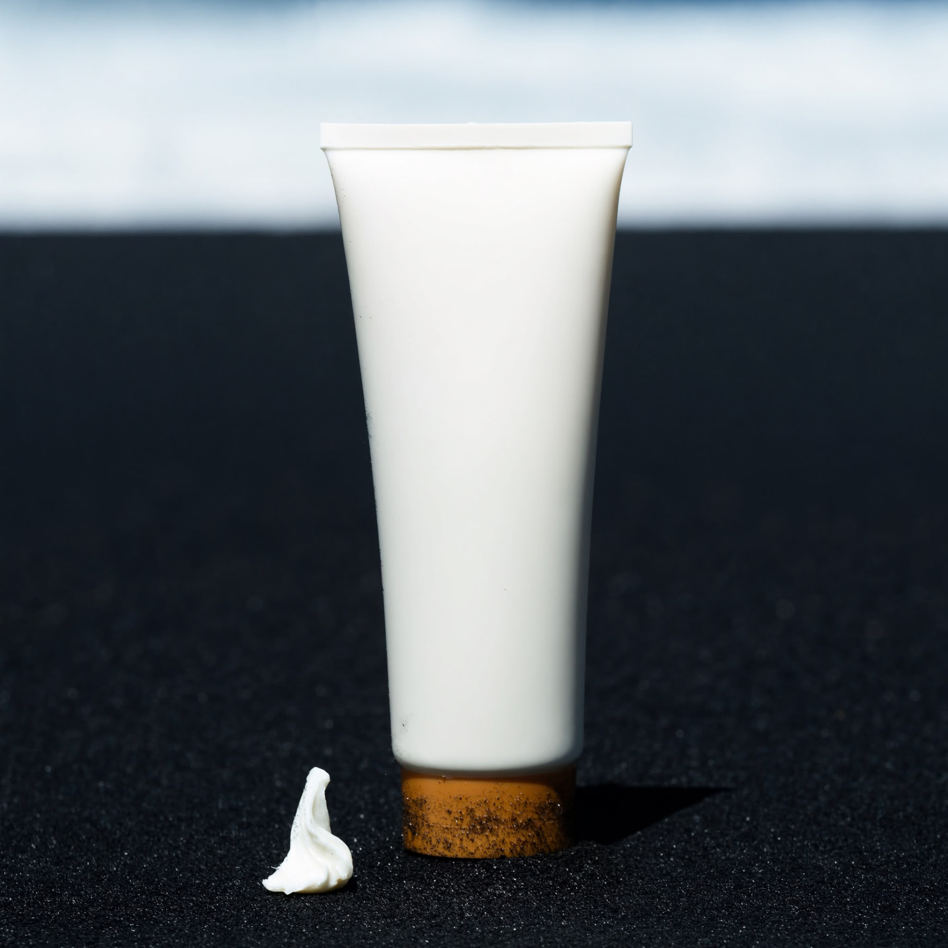 Tube de soin cosmétique sur sable noir — image produit